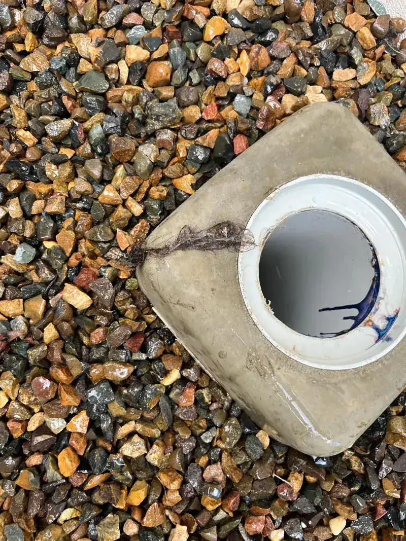 A concrete sewer inspection opening uncovered in gravel, ready for the drain machine