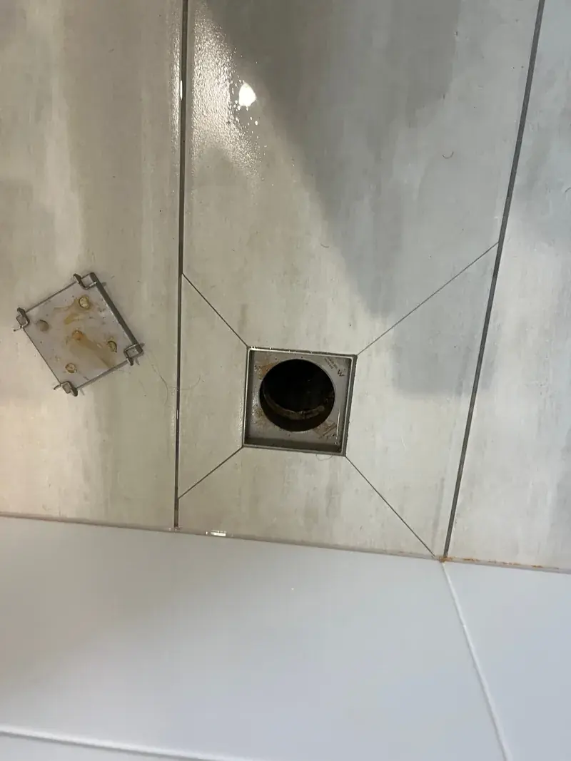 A tiled bathroom floor waste with the grate removed during a bathroom plumbing repair