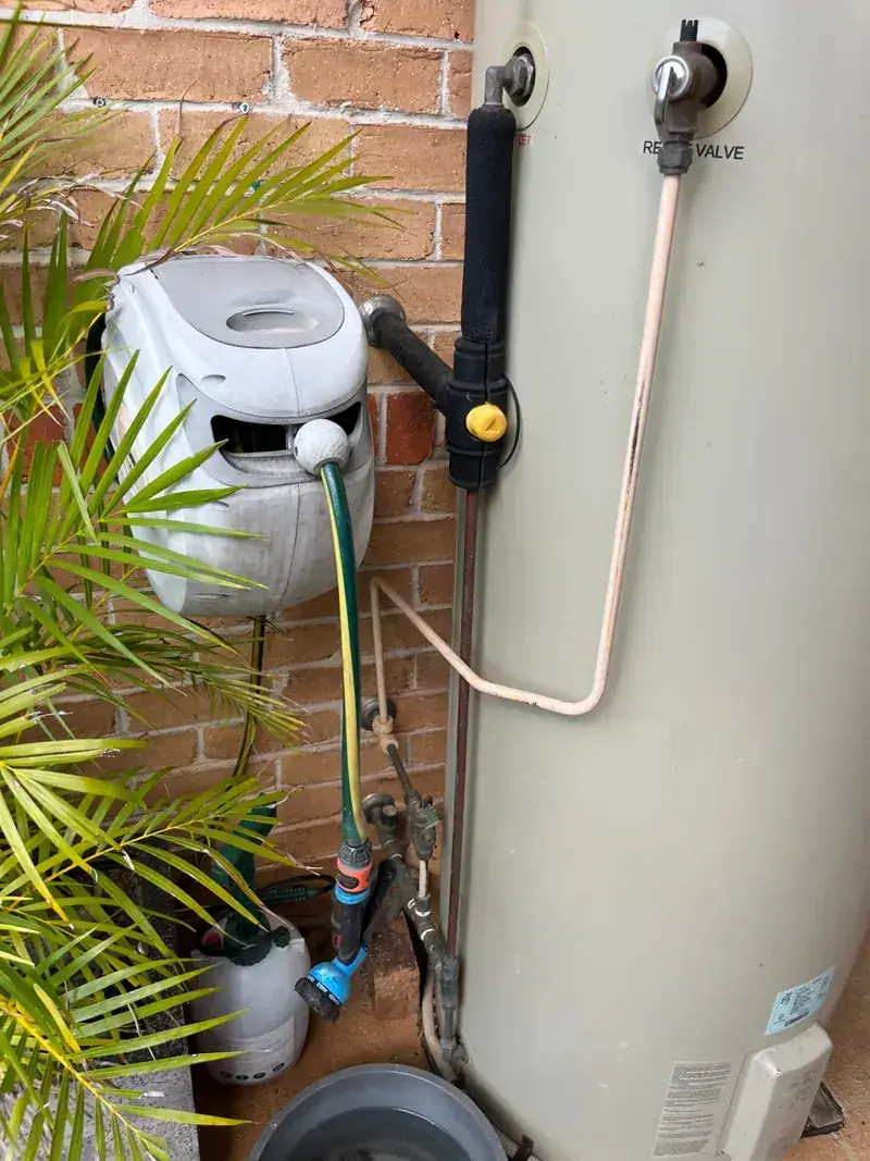 Copper and poly pipework with isolation valves run neatly along a brick wall