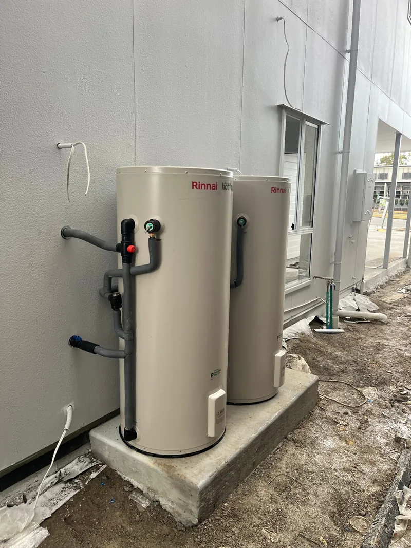 Two Rinnai electric hot water storage tanks installed side by side on a concrete pad